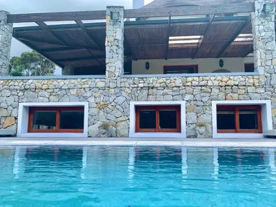 a house with a swimming pool and a stone wall at The Guardian Hermanus Luxury Self-Catering Hemel en Aarde Valley in Hermanus