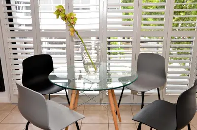 a glass table with four chairs and a vase with a flower at Concord Modern Apartment in Stellenbosch in Stellenbosch