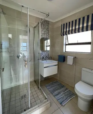 a bathroom with a shower and a toilet and a sink at By Die See in Gordonʼs Bay