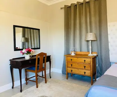 a bedroom with a desk and a bed and a mirror at Bonne Chance Cottage in Paarl