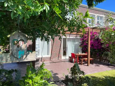 a garden with a table and a house at Sunset Beach Living Guesthouse in Cape Town