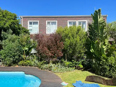 a house with a swimming pool in a garden at Sunset Beach Living Guesthouse in Cape Town