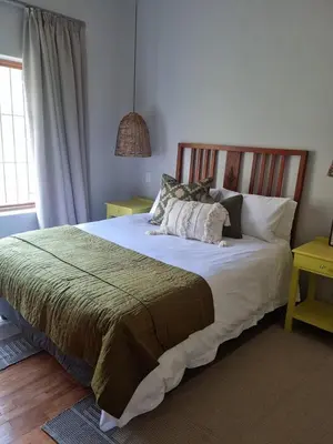 a bedroom with a large bed with white sheets and pillows at River Edge in Romansrivier