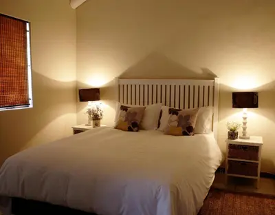 a bedroom with a large white bed with two lamps at River Edge in Romansrivier