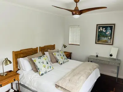 a bedroom with a white bed with a ceiling fan at Villa Voigt in Hermanus