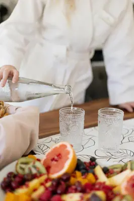a chef is pouring water into glasses on a table with fruit at La Roche Estate in Franschhoek