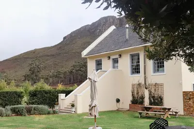 a white house with a mountain in the background at La Roche Estate in Franschhoek