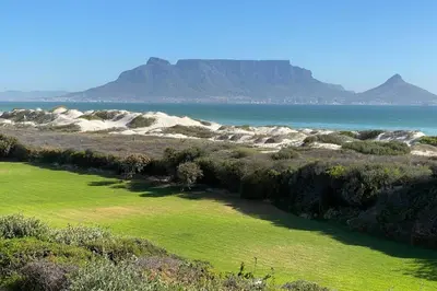 a view of the beach with mountains in the background at Dolphin Beach Villa E24 direct access to the beach in Cape Town
