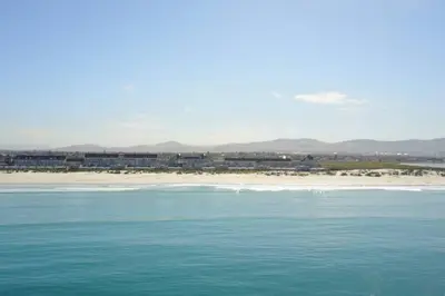 a body of water with a beach in the background at Dolphin Beach Villa E24 direct access to the beach in Cape Town