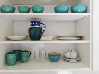a shelf filled with bowls and plates and vases at Bachelor cottage STRICTLY HALAAL Garlandale Rondebosch East in Cape Town