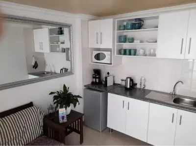 a kitchen with white cabinets and a counter top at Bachelor cottage STRICTLY HALAAL Garlandale Rondebosch East in Cape Town