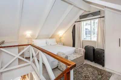 a white bedroom with a bed and a window at Invergara in Cape Town