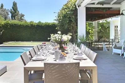a long table with glasses and flowers on a patio at Le Bas De Laine in Franschhoek