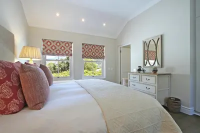 a bedroom with a large bed and two windows at Le Bas De Laine in Franschhoek