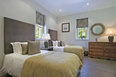 a bedroom with two beds and a dresser and a mirror at Le Bas De Laine in Franschhoek