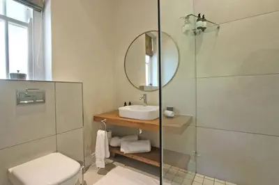 a bathroom with a sink and a shower with a mirror at Le Bas De Laine in Franschhoek