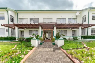 a large white building with a brick walkway at Fairway Holiday Accommodation in Hermanus