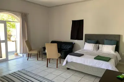 a bedroom with a bed and a table and chairs at Le Grec Wine Tram Apartment #3 in Franschhoek
