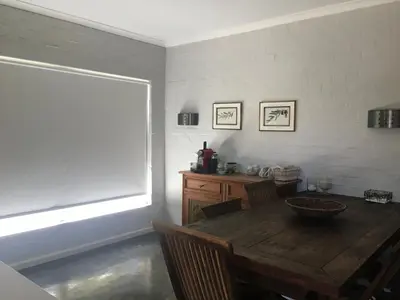 a dining room with a wooden table and a window at Olive Cottage in Hermanus
