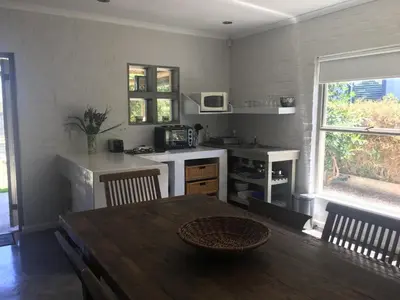 a kitchen and dining room with a table and a table and a table at Olive Cottage in Hermanus
