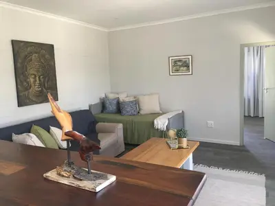 a living room with a couch and a table at Olive Cottage in Hermanus