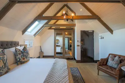 a bedroom with a large bed and a chair at Southern Sun de Wagen in Stellenbosch