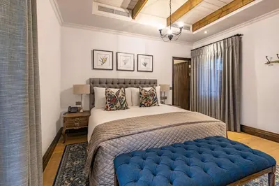 a bedroom with a large bed with a blue ottoman at Southern Sun de Wagen in Stellenbosch