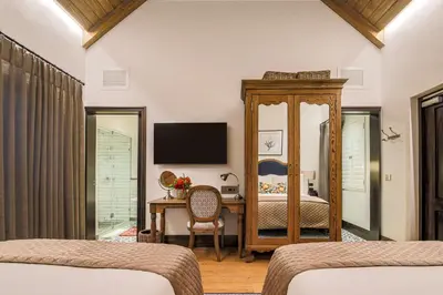 a bedroom with two beds and a desk and a television at Southern Sun de Wagen in Stellenbosch