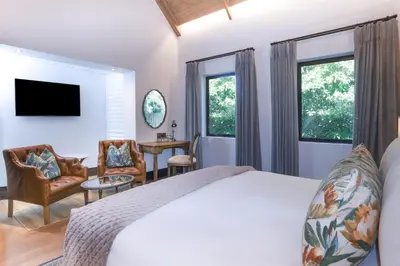 a bedroom with a bed and two chairs at Southern Sun de Wagen in Stellenbosch