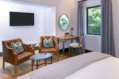 a bedroom with a bed and a table and chairs at Southern Sun de Wagen in Stellenbosch