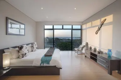 a bedroom with a large bed and a large window at Gecko House in Pringle Bay