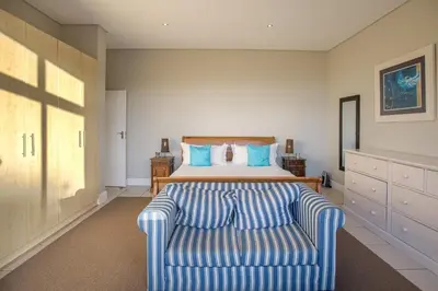 a bedroom with a bed and a blue couch at Gecko House in Pringle Bay