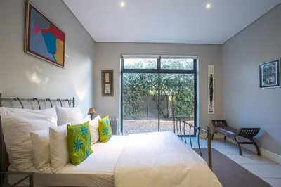 a bedroom with a large white bed and a window at Gecko House in Pringle Bay