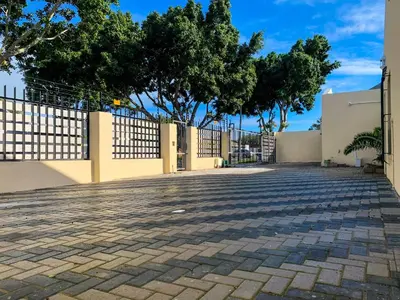 a driveway with a fence and trees in the background at ALIAHIDI in Cape Town