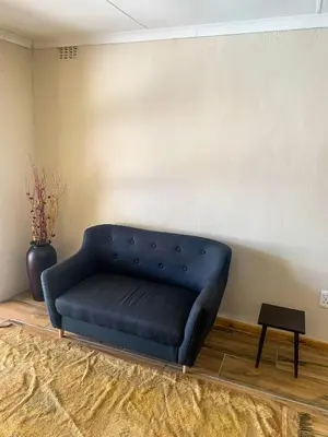 a blue couch sitting in a room next to a wall at ALIAHIDI in Cape Town