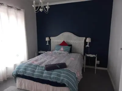 a bedroom with a bed with a blue wall at Thundering waves in Bettyʼs Bay
