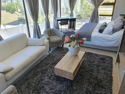 a living room with a couch and a bed and a table at The Model House in Cape Town