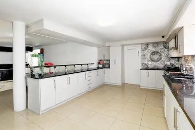 a kitchen with white cabinets and a tile floor at The Model House in Cape Town