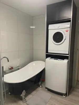 a bathroom with a bath tub and a washing machine at Jackie’s 3 bedroomed secure beach front apartment Strand Golden Mile in Strand
