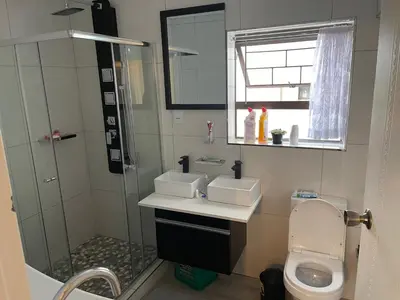 a bathroom with a sink and a shower and a toilet at Jackie’s 3 bedroomed secure beach front apartment Strand Golden Mile in Strand