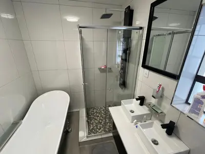 a bathroom with a shower and a toilet and a sink at Jackie’s 3 bedroomed secure beach front apartment Strand Golden Mile in Strand