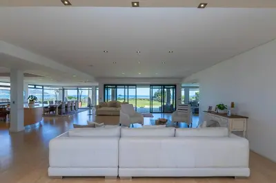 a living room with a white couch and chairs at Villa Paradis - ocean front with views to behold! in Cape Town