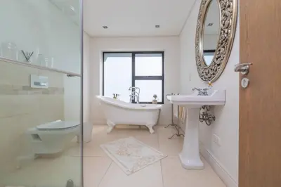 a bathroom with a tub and a sink and a mirror at Villa Paradis - ocean front with views to behold! in Cape Town