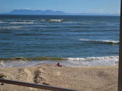 a person sitting on the beach near the ocean at On The Beach At Strand in Strand