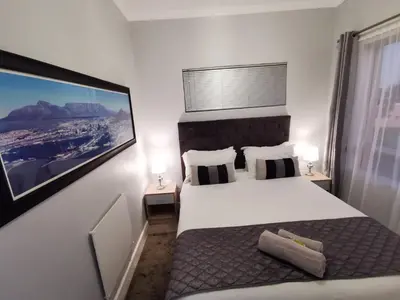 a bedroom with a large white bed with two lamps at Zebra Place in Cape Town