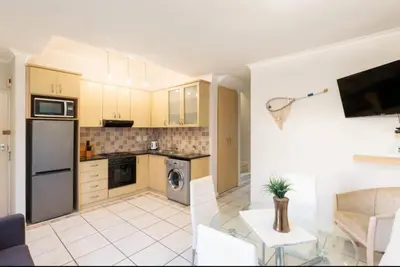 a kitchen with a stove top oven next to a living room at Waters Breakaway in Bloubergstrand