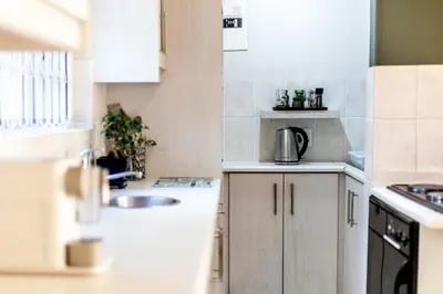 a kitchen with white cabinets and a sink at Seagull Hermanus in Hermanus