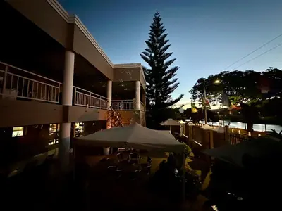 a building with tables and umbrellas in front of a tree at Sunset Boulevard Riverlodge in Paarl