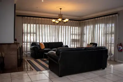 a living room with two leather couches and a chandelier at Balmoral Lodge in Bellville