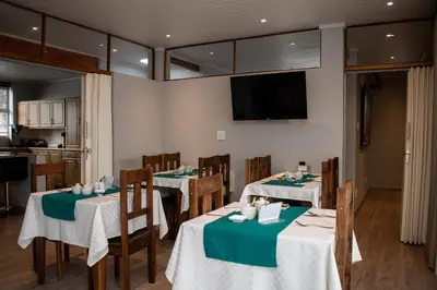 a dining room with two tables and a tv at Balmoral Lodge in Bellville